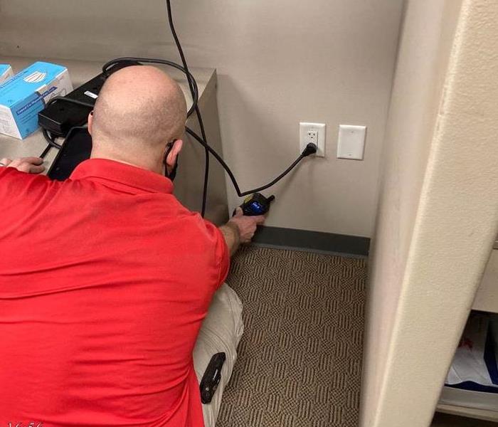 Technician testing the moisture content of the wall with a moisture meter.