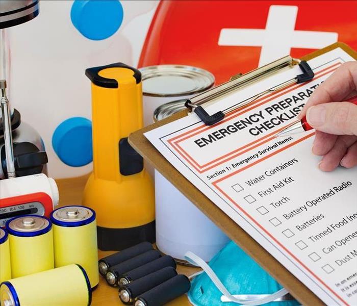 Emergency preparation list on a clip board, batteries, gallons of water, 